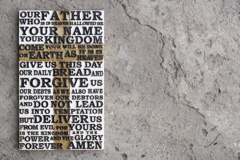 Wooden carved word of the Lord`s Prayer on the grey concrete background. Dreamstime/TCA