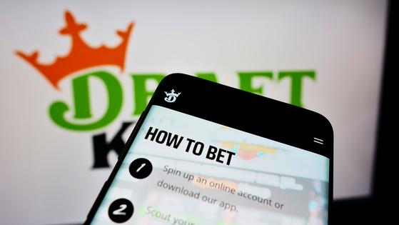 Mobile phone with website of American sports betting company DraftKings Inc. on screen in front of logo. Dreamstime/TCA