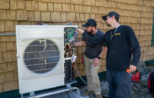 Workers install an air-source heat pump at a home in Charlotte, Vt. Robert Nickelsberg/Getty Images