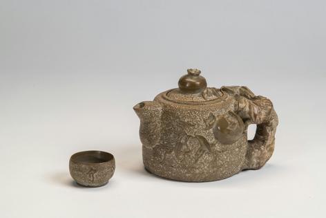 A teapot and cup made out of slate by Homei Iseyama, decorated with depictions of pomegranates and leaves evoking his connection with nature as a landscape gardener and bonsai master.
              Gift of the artist's family via Smithsonian American Art Museum