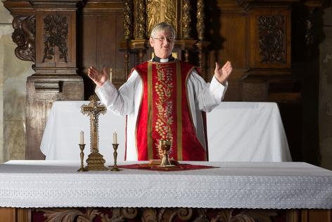 Christian priest blessing the hosts and chalice in a 17th-century church. Dreamstime/TCA