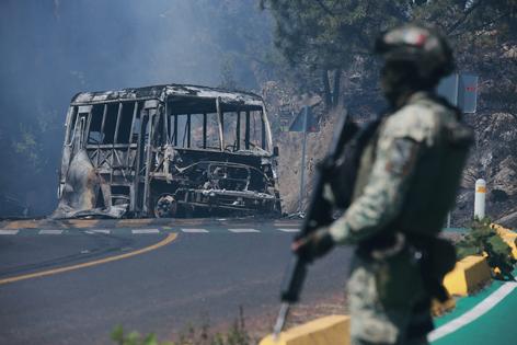 A soldier stands guard by a charred vehicle in Michoacán state, Mexico, on Feb. 22, 2026. AP Photo/Armando Solis