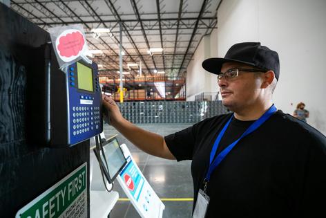 A worker swipes a time card to clock in at the beginning of their shift.
              halbergman/E+ via Getty Images