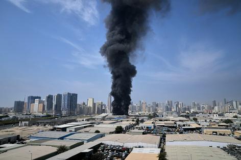 A plume of smoke rises from a warehouse in the industrial area of Sharjah City in the United Arab Emirates, following reports of Iranian strikes elsewhere in the region on March 1, 2026.  AP Photo/Altaf Qadri