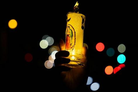 A protester holds up a candle with the image of La Virgen de Guadalupe while marching in Los Angeles during a January 2026 vigil in solidarity with immigrants facing raids in Minneapolis. Ronaldo Bolaños/Los Angeles Times via Getty Images