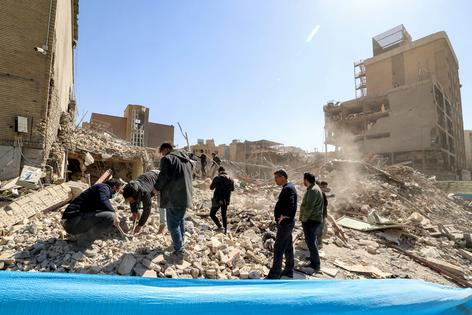 People inspect the rubble of a collapsed building on March 3, 2026, kicking up dust that can harm their health. U.S. Secretary of Defense Pete Hegseth said on March 13, 2026, that 15,000 targets had been hit since the U.S. and Israel began bombing Iran on Feb. 28.
Atta Kenare/AFP via Getty Images