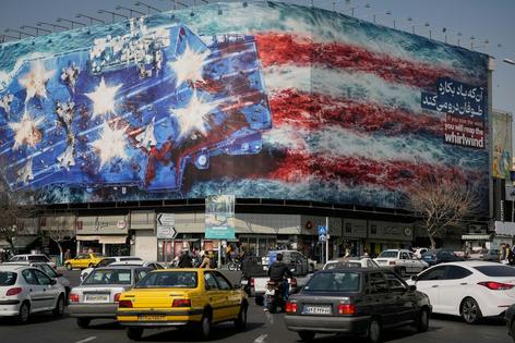 Vehicles pass a billboard in Tehran, Iran, on Feb. 22, 2026, depicting a U.S. aircraft carrier with damaged fighter jets on its deck.
              AP Photo/Vahid Salemi