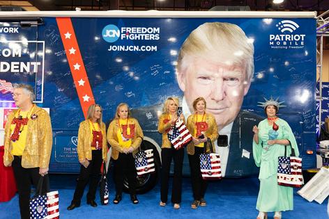 Attendees wearing MAGA merch stand next to an image of Trump at the Conservative Political Action Conference in Grapevine, Texas, on March 25, 2026. Leandro Lozada AFP/Getty Images