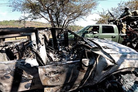 Members of the army onboard a truck are seen next to a burned car used to block roads while Mexican drug lord 