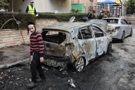A child looks at the damage as first responders work at a site hit during an Iranian strike over Petah Tikva on March 31, 2026. Iran fired missiles across the Middle East on March 31 as its capital was hit by fresh explosions, after US President Donald Trump threatened the country's key oil export hub, power stations and desalination plants. (Photo by Jack GUEZ / AFP via Getty Images) /