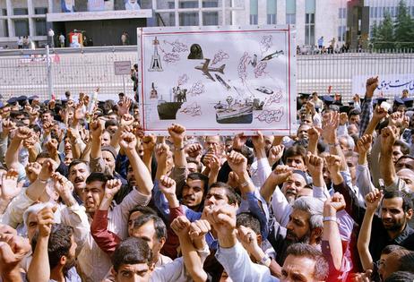 At a mass funeral for 76 of the 290 people killed in the shootdown of Iran Air 655, mourners hold up a sign depicting the incident.
AP Photo/CP/Mohammad Sayyad