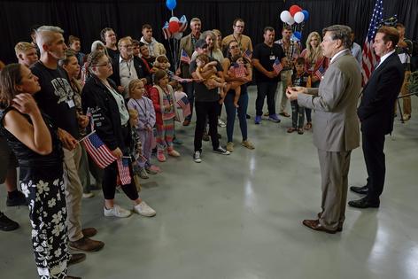 Newly arrived South Africans listen to U.S. Deputy Secretary of State Christopher Landau deliver welcome statements in a hangar near Washington Dulles International Airport on May 12, 2025. Chip Somodevilla/Getty Images