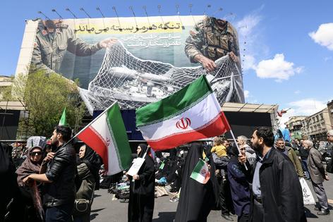 Iranians hold national flags in Tehran's Revolution Square on April 8, 2026, after the United States and Iran agreed to a two-week ceasefire.  Atta Kenare/AFP via Getty Images