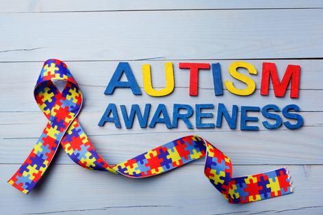 World Autism awareness and pride day or month with Puzzle pattern ribbon on blue wooden background. Dreamstime/TCA