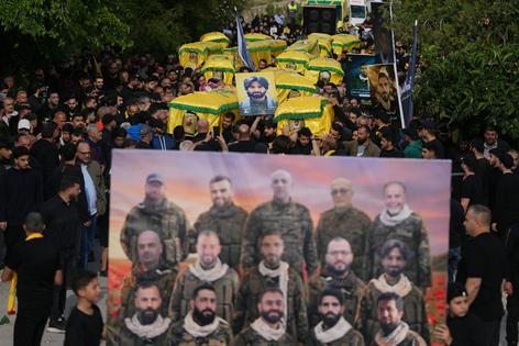 Mourners carry the coffins of Hezbollah fighters killed in the war between Hezbollah and Israel during a funeral in Kfar Sir, Lebanon, on April 21, 2026.
              AP Photo/Hassan Ammar