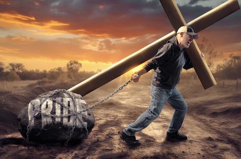 Man pulling cross and pride. A man struggles to both carry the cross and pull a heavy stone. Dreamstime/TCA