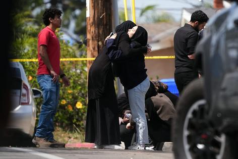 People comfort one another near the scene of a shooting outside the Islamic Center of San Diego on May 18, 2026, in San Diego.  AP Photo/Gregory Bull