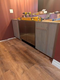 There are three cabinets in this photo. A sink base is to the left of the refrigerator/freezer. A trash-can cabinet and small slide-out shelf cabinet are to the right. This is the bar area of a basement speakeasy. (Tim Carter/Tribune Content Agency/TNS)