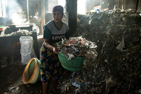 A worker carries a basket of plastic waste, wood and coconut husks to be used as fuel to fry tofu at a factory in Sidoarjo, Indonesia, in 2025. Burning waste is a common way to cut fuel costs, but studies have found high levels of microplastics in the tofu from these factories, toxic ash inside the buildings and hazardous levels of air pollution.
              Robertus Pudyanto/Getty Images