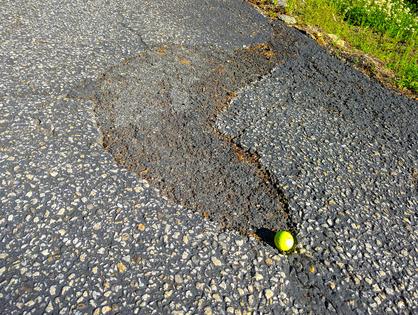 This asphalt patch was installed two years ago. It was a product in a bag bought from a home center. It started to fail within one year. The golf ball is for scale. (Tim Carter/Tribune Content Agency/TNS)