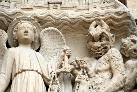 Angel and devil. Medieval church sculpture detail - Our Mother Cathedral in Paris. Dreamstime/TCA