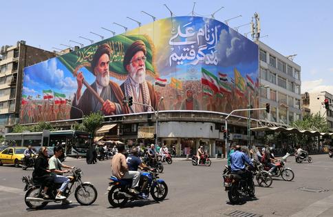 People ride motorcycles past a large billboard in central Tehran on June 8, 2026. Atta Kenare/AFP via Getty Images