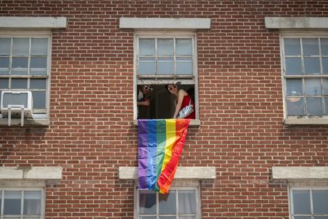 People drape a rainbow flag from a window during the 2026 New York City Pride March.
Noam Galai/Getty Images