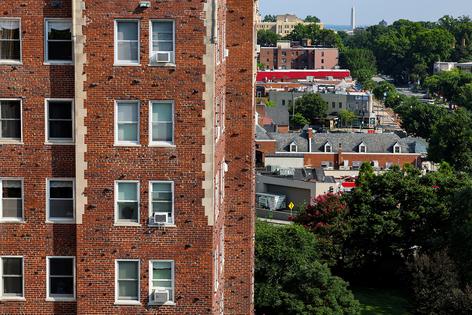 Air conditioner units sit in windows of an apartment building on July 20, 2022, in Washington, DC. (Anna Moneymaker/Getty Images/TNS)