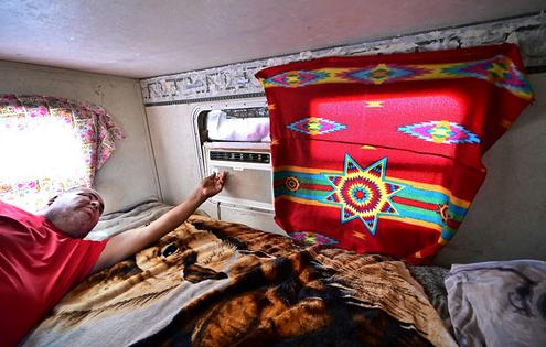 Elbert Yazzie adjusts his air conditioning unit in Tuba City, Ariz., in 2025. Frederic J. Brown/AFP via Getty Images