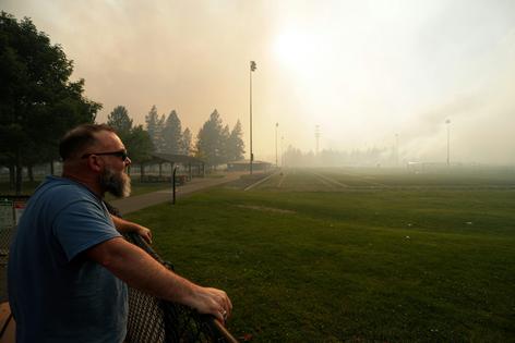 Andrew Rowley watches a wildfire burning from a distance after evacuating his home on Aug. 1, 2026, in Spokane, Wash. AP Photo/Young Kwak