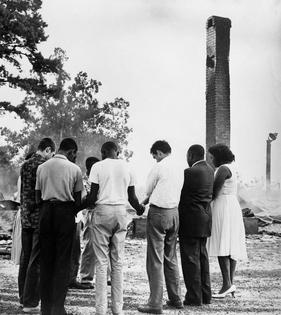 Members of the Student Nonviolent Coordinating Committee pray beside the ruins of a burned church near Dawson, Ga., in 1962. Bettmann Archive/Getty Images