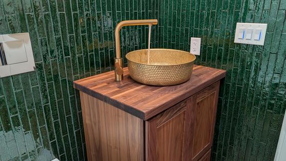 This solid-brass vessel sink is installed on a solid walnut butcher block top. The crackled green subway tile walls create a dramatic look. (Tim Carter/Tribune Content Agency/TNS)