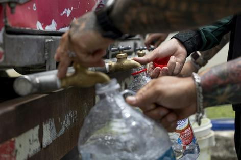 Residents collect water from a tanker truck amid government-imposed water rationing in San Juan, Puerto Rico, in August 2026. Ricardo Arduengo/AFP via Getty Images