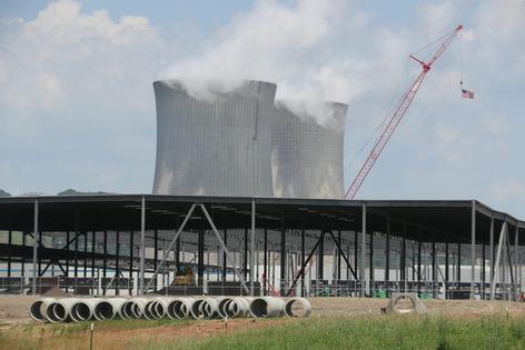 The cooling towers of an electric station are seen beyond an Amazon Web Services data center construction project in Berwick, Pa. Paul Weaver/SOPA Images/LightRocket via Getty Images