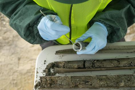 The author works on gathering soil samples in a field near Mill 19 in Hazelwood. Kevin Lorenzi/Mellon College of Science via Carnegie Mellon University