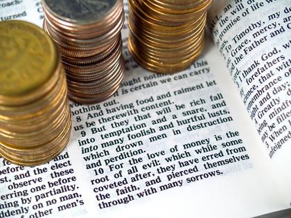 I Timothy 6:10 Love of Money 1. A Bible opened to I Timothy 6:10 with coins around it. Dreamstime/TCA