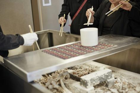 A cremation service with family members collecting the bones of the deceased.
              Arrow/DigitalVision via Getty images