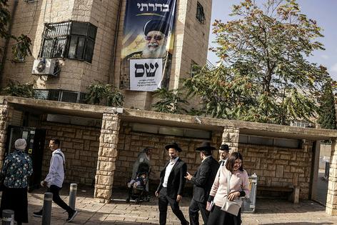 Orthodox Jews walk past an election campaign banner for the Haredi religious political party Shas, bearing a portrait of former Sephardi Chief Rabbi Ovadia Yosef, in Jerusalem on Oct. 15, 2026.
              John Wessels/ AFP via Getty Images