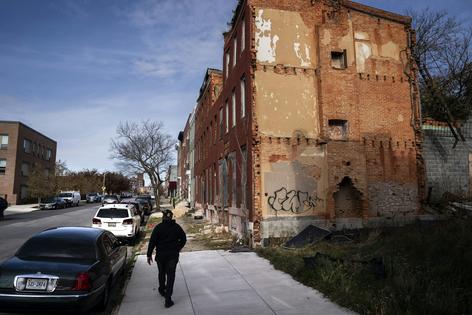 A community partnership manager with Baltimore’s Group Violence Reduction Strategy walks past vacant buildings in November 2025 after trying to offer support services to people at high risk of violence.
              Jabin Botsford/The Washington Post via Getty Images