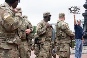 TOPSHOT - Protesters demonstrate near members of the National Guard as they stand watch outside Union Station in Washington, DC, on August 20, 2025. US President Donald Trump on August 11 deployed military and federal law enforcement to curb violent crime in Washington, as he seeks to make good on his campaign pledge to be a