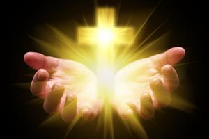 Hands cupping cross. Dreamstime/TCA