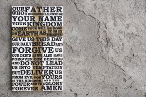 Wooden carved word of the Lord`s Prayer on the grey concrete background. Dreamstime/TCA