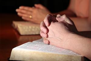 Man, woman, praying with Bibles. Dreamstime/TCA