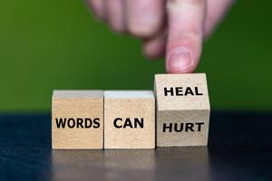 Hand turns cube and changes the expression words can hurt to words can heal. Dreamstime/TCA