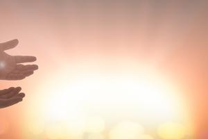 Jesus Christ hands showing scars for Thomas over blurred cross sunset background. Dreamstime/TCA