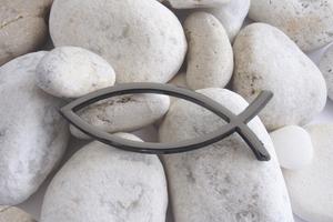 Christian religious Fish sign over white pebbles. Dreamstime/TCA
