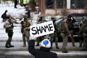 MINNEAPOLIS, MINNESOTA - JANUARY 07: An onlooker holds a sign that reads 