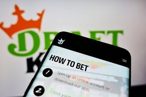 Mobile phone with website of American sports betting company DraftKings Inc. on screen in front of logo. Dreamstime/TCA