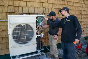 Workers install an air-source heat pump at a home in Charlotte, Vt. Robert Nickelsberg/Getty Images