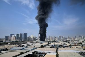 A plume of smoke rises from a warehouse in the industrial area of Sharjah City in the United Arab Emirates, following reports of Iranian strikes elsewhere in the region on March 1, 2026.  AP Photo/Altaf Qadri